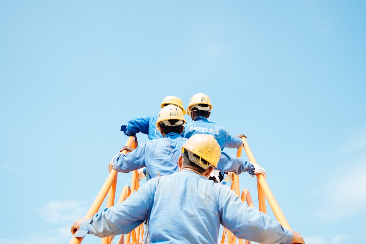 Handwerker-Team trägt eine Leiter zur Baustelle